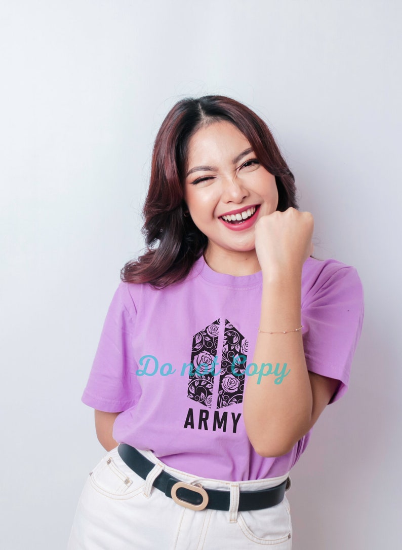 Op de afbeelding: Een paars T-shirt met een zwart-witte afbeelding van het BTS-logo met rozen. De tekst "Do not copy" en "ARMY" staat op het T-shirt gedrukt.