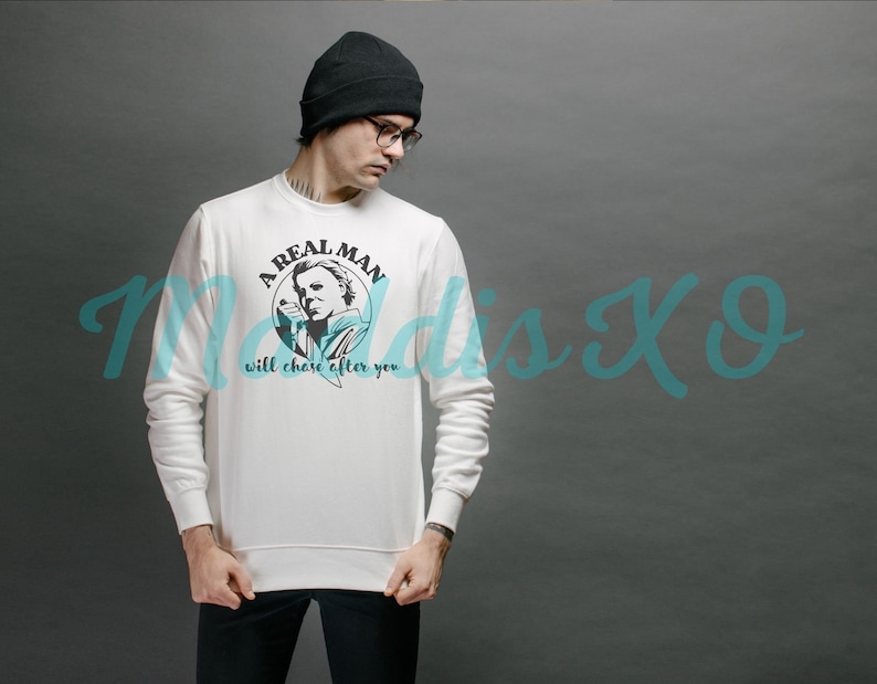 May include: White sweatshirt with a black and white graphic of a man with a knife and the text "A Real Man Will Chase After You".