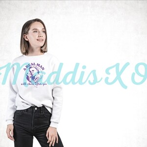 May include: White sweatshirt with a graphic of a man holding a knife and the text "A real man will chase after you".