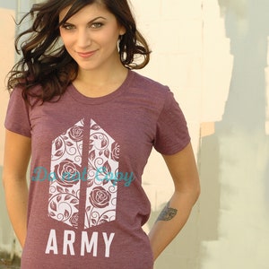 Op de afbeelding: Een maroon t-shirt met een wit bloemmotief en de tekst "ARMY".