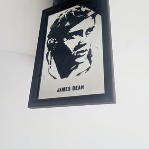 May include: Black and white silhouette portrait of James Dean in a black frame.