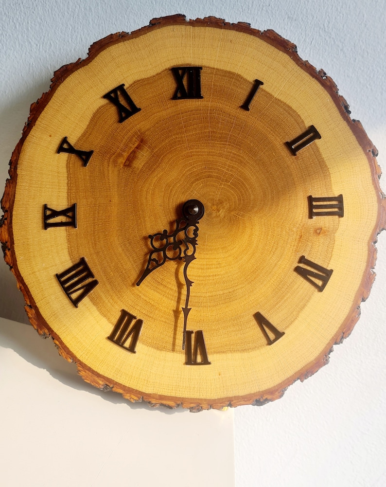 May include: A wooden clock with Roman numeral markings on a natural wood slice. The clock hands are black metal.
