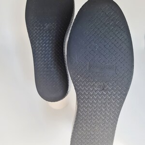 Puede incluir: Primer plano de las suelas negras de dos pares de zapatos. Las suelas tienen un patr&oacute;n texturizado y el tama&ntilde;o 39 est&aacute; impreso en la parte inferior.