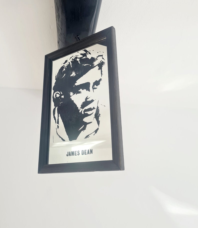 May include: A black and white silhouette of James Dean in a framed mirror with a black frame.
