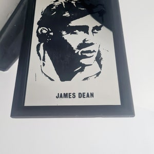 May include: Black and white framed mirror with a silhouette of James Dean's face and the text "JAMES DEAN" below.