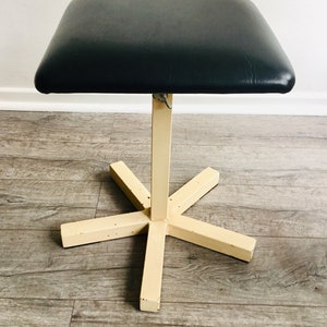 May include: A black padded stool with a cream-coloured metal base and a five-point star-shaped base.