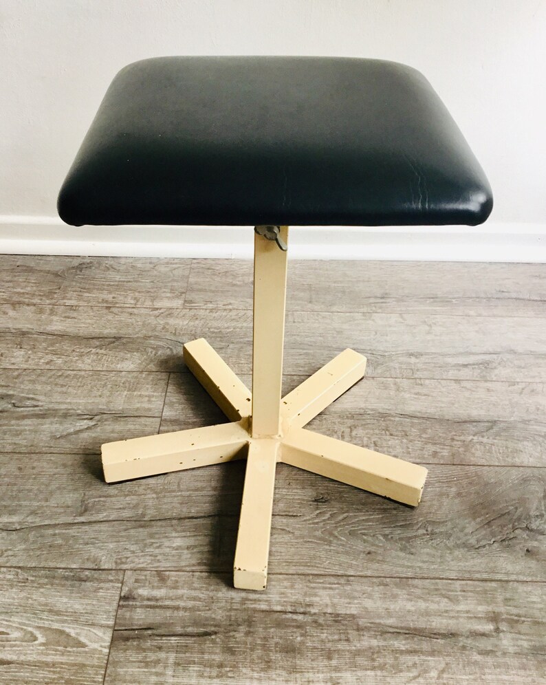 May include: A black padded stool with a cream-coloured metal base and a five-point star-shaped base.