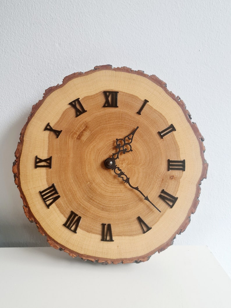 May include: A wooden clock with Roman numeral markings on a natural wood slice. The clock hands are black metal.