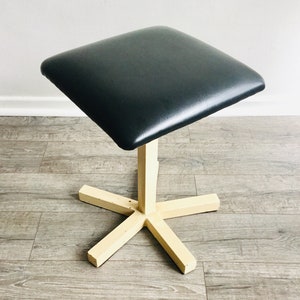 May include: A black upholstered square stool with a cream-coloured, five-pointed star base.
