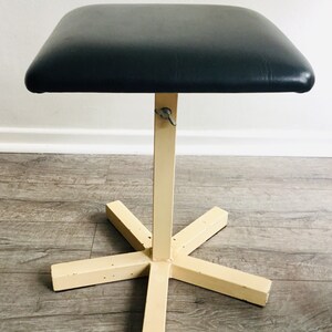 May include: A black padded medical examination table with a white metal base and a five-pointed star-shaped footrest.