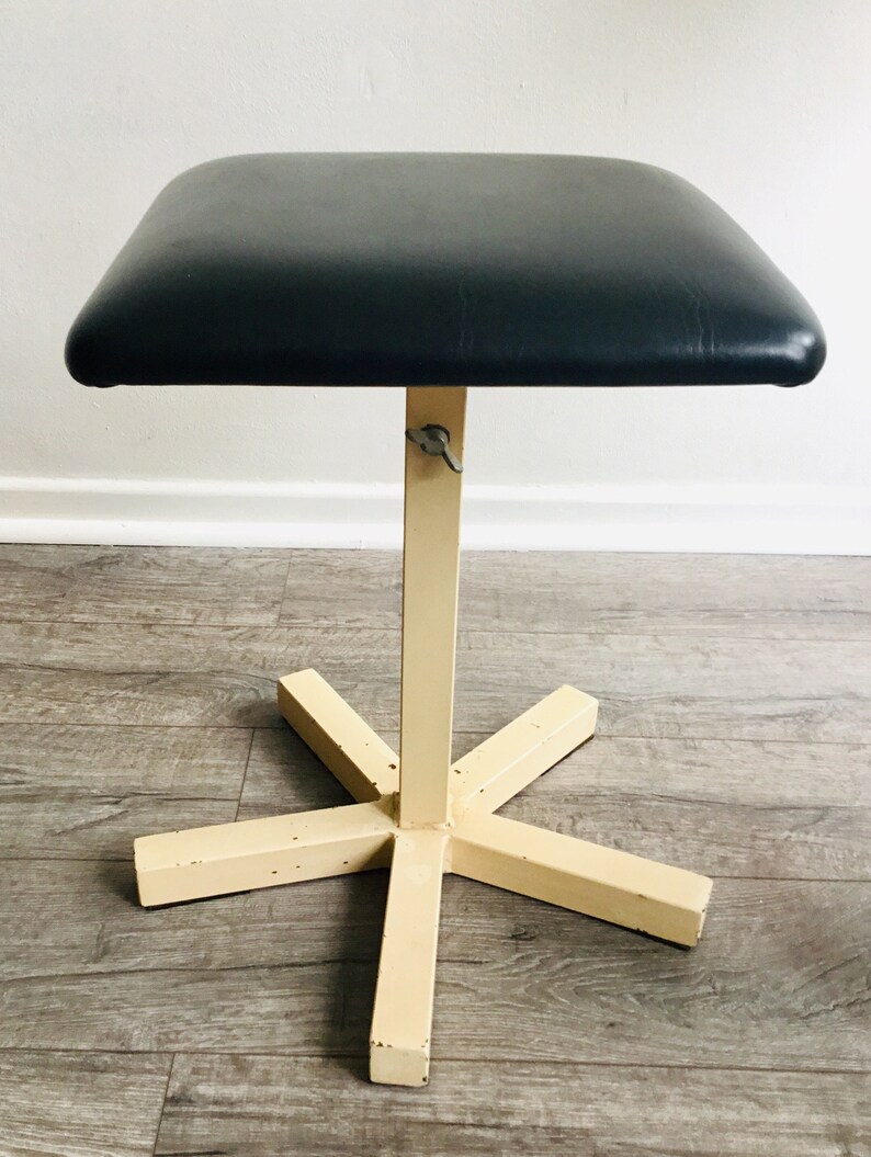May include: A black padded medical examination table with a white metal base and a five-pointed star-shaped footrest.