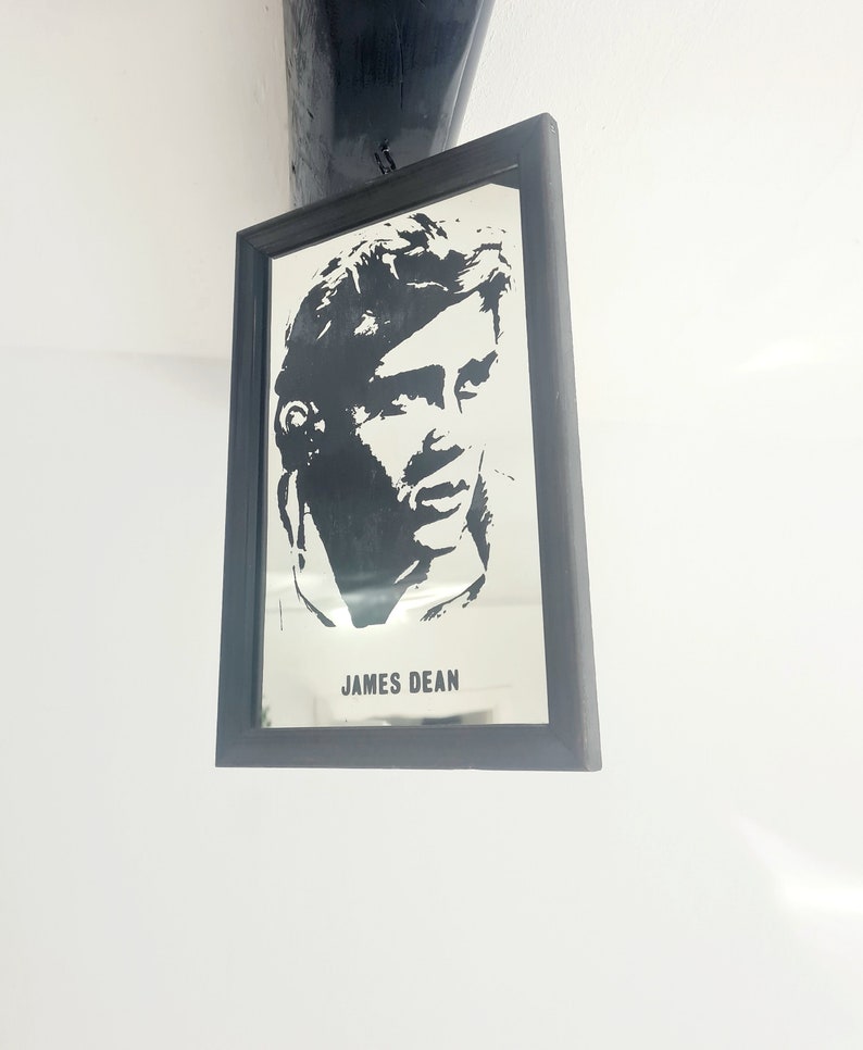 May include: Black and white silhouette of James Dean in a framed mirror. The mirror has a black frame and the text "JAMES DEAN" is printed below the image.