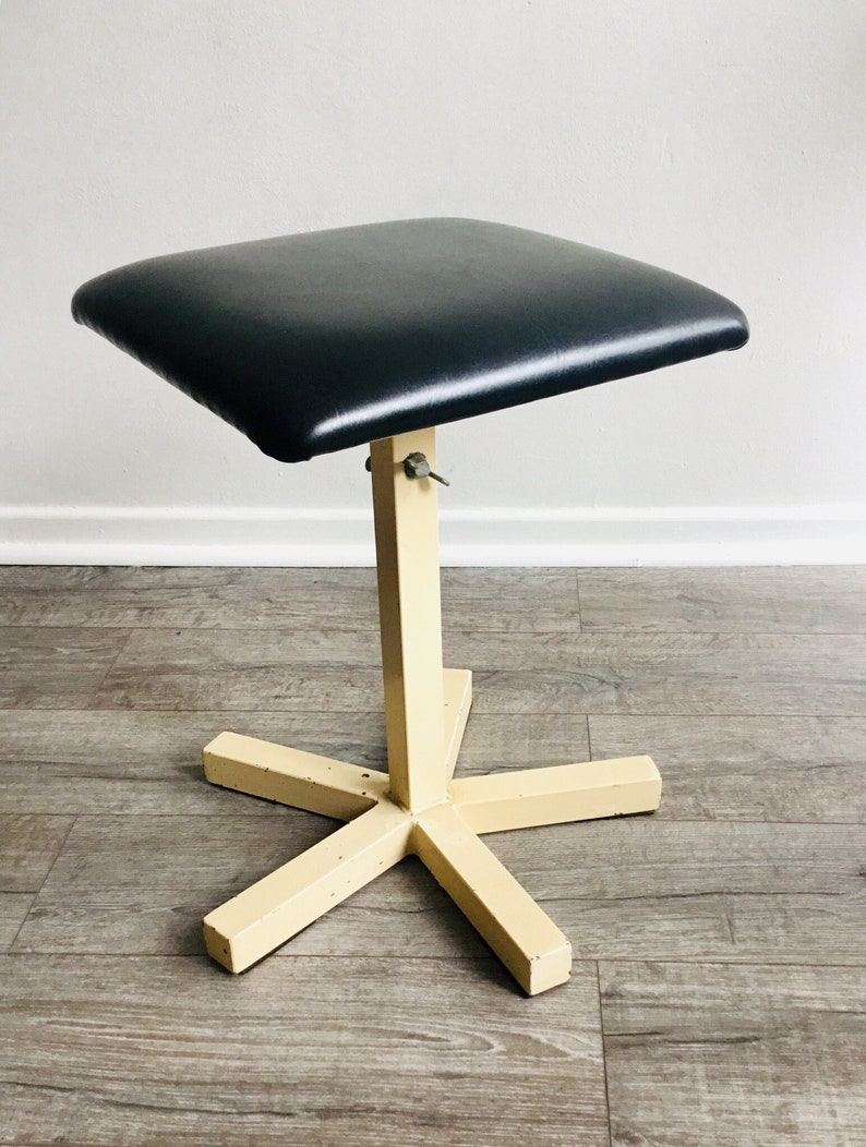 May include: A black padded stool with a cream-coloured metal base and a five-pointed star-shaped footrest.