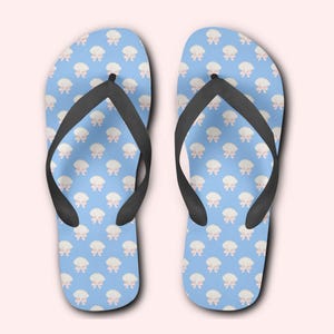 Op de afbeelding: Een paar blauwe slippers met een wit en roze strikmotief.
