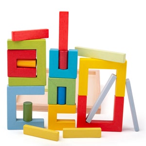 May include: A colorful wooden block stacking game with various shaped blocks in red, yellow, green, blue, and light blue. The blocks are arranged in a tower formation.