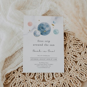 May include: A watercolour-style invitation for a first birthday party with a space theme. The invitation features planets, stars, and a rocket ship. The text reads "first trip around the sun Noah is One!"  Join us for a birthday party Saturday, August 10th at 11 AM. The William Home 1382 Taylor Road, Denver, CO 80014 RSVP to Emily by 10th May at youremail@email.com