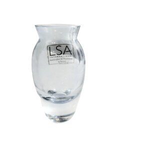 May include: A clear glass vase with a rounded body and a slightly flared top. The vase has a label that reads "LSA International Handcrafted & Mouthblown in Poland."