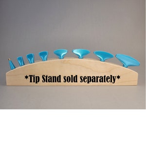 Puede incluir: Un conjunto de ocho puntas de pintura azules mostradas en un soporte de madera. El soporte es curvo y tiene el texto "*Tip Stand sold separately*" impreso en él.