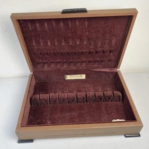 May include: Open wooden silverware storage box with a brown exterior and a burgundy velvet interior. The box is divided into compartments for cutlery and features the "Community" brand name on a small gold label.