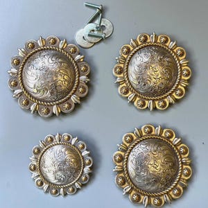 May include: Four circular metal conchos featuring intricate silver-toned floral engraving in the centre, surrounded by a gold-toned rope border and small gold-toned studs. Three screws and three metal washers are included for installation.