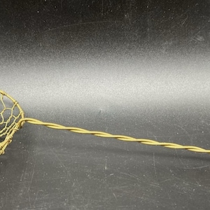 Könnte beinhalten: Ein Vintage-Schöpfer aus Messingdraht mit einem runden Korb mit Wabenmuster und einem langen, gedrehten Griff. Der Griff endet in einer Schlaufe. Dieses Küchenutensil wird wahrscheinlich zum Herausnehmen von Lebensmitteln aus heißen Flüssigkeiten verwendet.