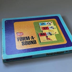 May include: A rectangular cardboard game box titled Ideal Form-A-Sound No. 2621. The box features a blue border, a yellow center panel, and a green graphic area displaying letter cards with mouth illustrations and the word baby with a child.