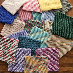 May include: A collection of square, hand-knitted washcloths in various colors and patterns. The cloths include solid colors like blue, yellow, and green, as well as striped and speckled designs. The washcloths are arranged on a wooden surface.