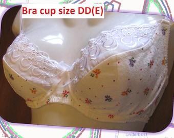 May include: A white bra with floral patterns and lace detailing. The bra features a delicate design with small, colourful flowers scattered across the fabric. The text "Bra cup size DD(E)" is visible at the top.