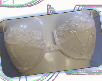 May include: White bra with floral lace detailing. The bra has a front closure and is displayed on a mannequin. The cups are decorated with rose-shaped lace, and the design is delicate and feminine.