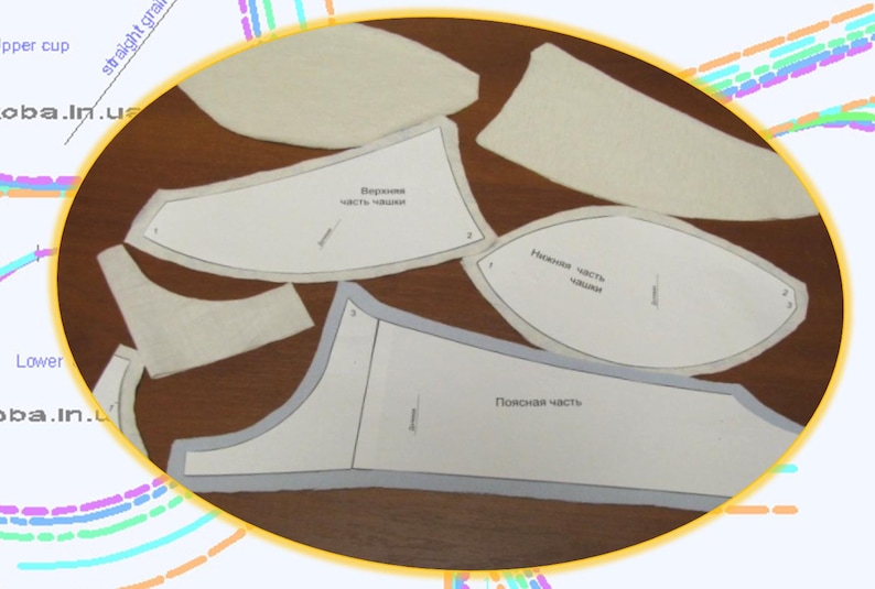 May include: A set of white fabric patterns for sewing a bra. The patterns are labeled in Russian. The patterns include pieces for the upper cup, lower cup, and side panels.
