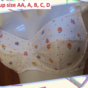 May include: White bra with a floral pattern in pink, yellow, and purple. The bra is displayed on a mannequin. Text at the top reads "Bra cup size AA, A, B, C, D".