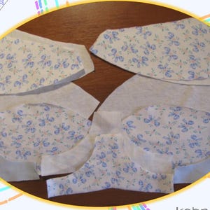May include: A set of fabric pieces for sewing a project. The fabric is white with a blue floral pattern. The pieces are cut out and ready to be sewn together.