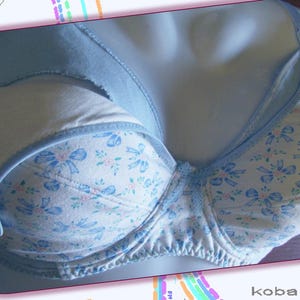 May include: A light blue bra with a white and blue floral pattern. The bra has a light blue strap and a white lining.