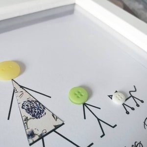 May include: A white frame with a white background and black stick figures. The stick figures have buttons for heads. The buttons are yellow, green, and white. The text "Red" is written in black ink at the bottom of the frame.
