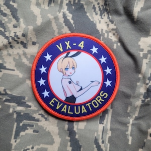 May include: A blue and red embroidered patch with a white circle in the center. The circle features a cartoon woman with blonde hair and a black dress. The text "VX-4 EVALUATORS" is written around the circle.