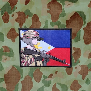 May include: An embroidered patch depicting an anime-style woman in a camouflage hat holding a rifle. The background is the flag of the Philippines.