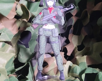 May include: Clear acrylic figure of a female soldier in camouflage fatigues, holding a rifle. The figure has a red collar and a green helmet. The background is a camouflage net.