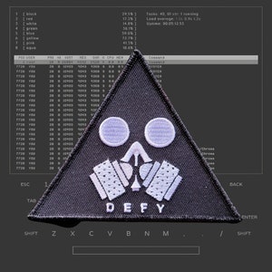 May include: A black triangular patch with a white gas mask design and the word "DEFY" in white letters. The patch is embroidered with a white outline.