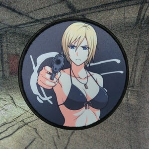 Peut inclure: Écusson rond représentant une femme de style anime aux cheveux blonds et aux yeux bleus, tenant un pistolet. Elle porte un haut de bikini noir et un collier. Le fond est gris foncé avec un motif blanc et une bordure noire.