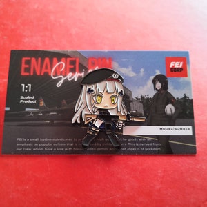 May include: A black and white enamel pin featuring an anime-style character with long white hair, a black beret, and a gun. The pin is labeled "1:1 Scaled Product" and "FEI CORP".
