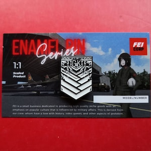 May include: A white enamel pin with a black and white design of a military rank insignia. The pin features the letters "GK" and a chevron design. The pin is part of a series called "Enamel Pin Series" and is a 1:1 scaled product. The pin is made by FEI Corp.