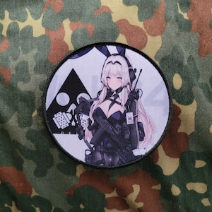 May include: A round black and white patch with a white background. The patch features a cartoon anime girl with long white hair, wearing a black outfit and holding a gun. The girl has a black bunny ear headband. The patch has a black border and the text "RE:L" in the lower left corner.
