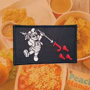 Può includere: Toppa ricamata nera con un personaggio dei cartoni animati bianco che tiene una lancia e la punta verso tre cosce di pollo rosse. Il personaggio indossa un cappello da cuoco bianco e una camicia bianca con un numero 8 rosso.