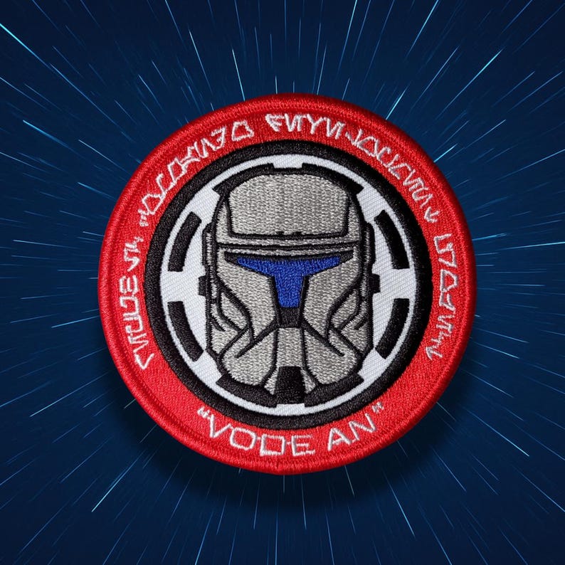 Pu&ograve; includere: Toppa ricamata con un design a casco grigio e dettagli blu, su sfondo circolare rosso. La toppa presenta bordi bianchi e neri, testo circolare e le parole "VODE AN".
