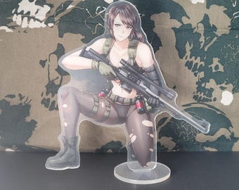 May include: A clear acrylic figure of a kneeling anime-style character holding a sniper rifle. The character is wearing a military-style outfit with black boots and gloves. The background features a camouflage pattern.