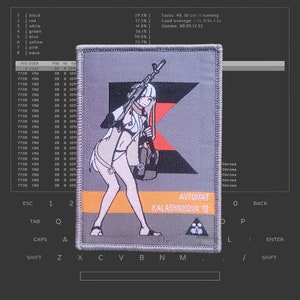 Può includere: Una toppa ricamata grigia e arancione con un'immagine stilizzata di una donna che tiene un fucile. Il testo "AVTOMAT KALASHNIKOVA 12" è stampato sulla toppa.