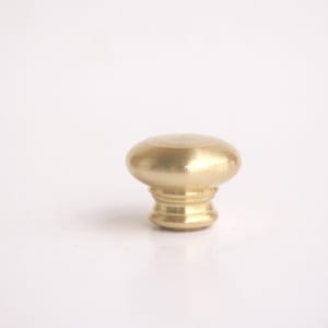 May include: A solid brass cabinet knob with a rounded top and a decorative base. The knob has a polished finish and is designed for use on drawers or cabinet doors. The hardware is shown against a white background.