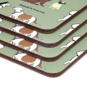 May include: A set of four green coasters with a brown border. Each coaster features a different cartoon dog breed, including a pug, a bulldog, and a husky. The coasters are stacked on top of each other, with the top coaster showing a bulldog. The text "Buggle Berry Productions" is printed on the coaster.
