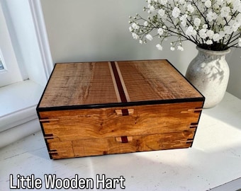 May include: A handcrafted wooden box with two drawers, featuring a natural wood grain finish. The box has a dark border and a decorative stripe down the center. The text "Little Wooden Hart" is at the bottom.