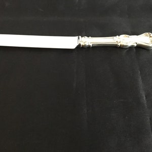 May include: A silver butter knife with an ornate handle.